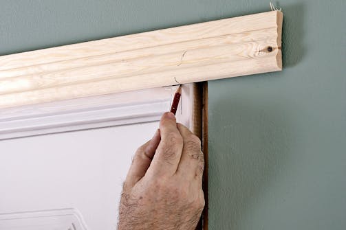 Vaakalistan nostaminen paikoilleen ja kynällä merkkaaminen Oven peitelista